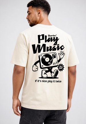 Man wearing a light-colored t-shirt with a black graphic of a walking vinyl record player and text promoting playing music all day on the back.