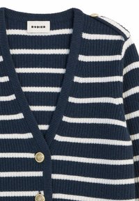 Marineblauwe en witte gestreepte cardigan met een v-hals ontwerp, textuurgaren stof en gouden knoopaccenten op de schouder.