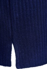 Primer plano de tela de punto azul marino con canalé vertical y una pequeña abertura en el borde inferior.