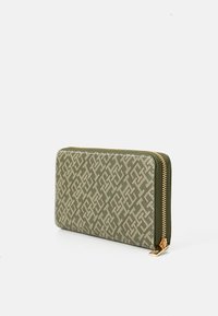 Green patterned wallet with a geometric design, featuring a gold zipper and a textured fabric finish, rectangular shape, and sleek profile.