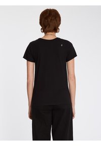 T-shirt en coton noir à manches courtes, col rond et manches retroussées. Présente un petit logo au niveau du haut du dos.