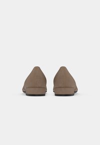 Brown suede low-heel shoes with a smooth texture and a tapered design. Rear view shows rounded heel and minimalist aesthetic.