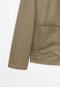Khaki jack met een gladde textuur, lange mouwen en een voortasje met een gestikte rand. De stof lijkt duurzaam en lichtgewicht.