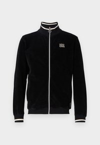 Giubbotto in corduroy nero con colletto alto, accenti a strisce bianche sul colletto e sui polsini, zip frontale e logo ricamato sul petto.