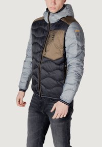 Polstret jakke med en blanding af marineblå, lys grå og khaki paneler, lynlåslommer, hætte og elastiske manchetter med stribe detaljer.