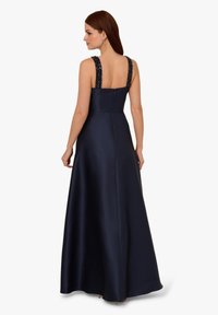 Granatowa satynowa suknia wieczorowa z koralikowymi ramiączkami, kwadratowym dekoltem z tyłu i pełną długością spódnicy. Posiada zamknięcie na zamek błyskawiczny z tyłu.
