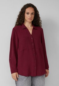 Bordeaux langemouw blouse met kraag, knoopsluiting aan de voorkant en twee borstzakken. Gelaagd stof met een relaxte pasvorm.