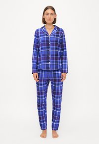 Ensemble de pyjama à carreaux avec des tons de bleu et de violet, comprenant une chemise à boutons avec un col en pointe et un pantalon assorti, fabriqué en tissu doux.