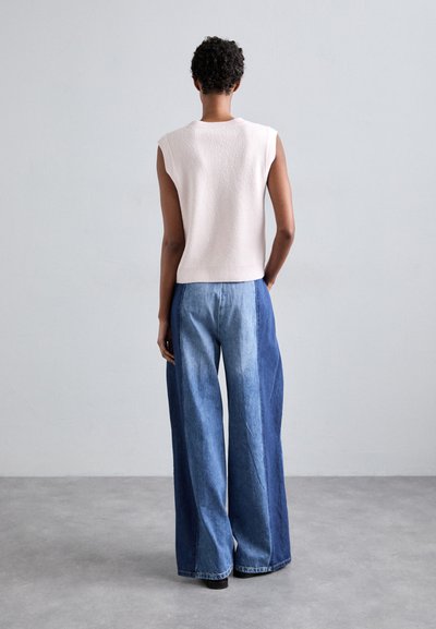 Lichtroze, mouwloze gebreide top met subtiele textuur, gecombineerd met wijde, twee-tonen blauwe denim broek. Glad stof en relaxte pasvorm.