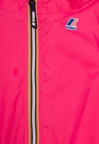 Giacca leggera di un vivace colore rosa brillante con cerniera centrale dotata di un tirante nero, accentuata da strisce a contrasto in giallo, nero e grigio.