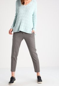 Ljusblå kabelstickad tröja med v-ringning, i kombination med grå tapered byxor och svarta sneakers. Strukturerad tyg och lös passform.