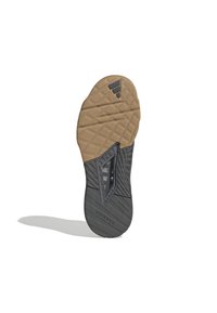 Semelle de chaussure présentant un design texturé avec une combinaison de caoutchouc gomme et noir. Comprend des rainures pour l'adhérence et un logo de la marque.