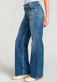 Wijde blauwe denim jeans met een hoge taille, vijf knopen en subtiele vervaging. De stof heeft een gladde textuur met een klassieke jeansafwerking.