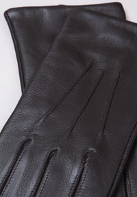 Brown leather gloves featuring a smooth texture, three horizontal seams on the back, and a fitted design for a sleek appearance.