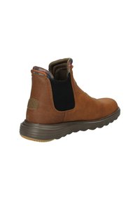 Botte de cheville en daim marron avec des panneaux élastiques, semelle en caoutchouc texturée et doublure à carreaux accentuée sur le col. Bout arrondi et design minimaliste.