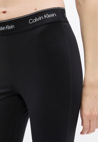 Čierne legíny z mäkkého a elastického materiálu, s širokým pásom s brandingom "Calvin Klein". Hladké, bez viditeľných vzorov alebo akcentov.