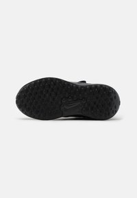 Semelle extérieure noire de chaussure de sport avec une surface texturée dotée de motifs ovales et d'un logo central, offrant traction et stabilité.