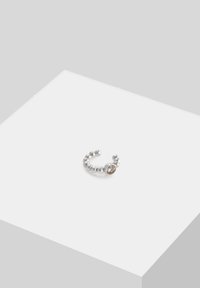 Anello in argento con perla centrale di forma circolare in pietra marrone, con un design flessibile e aperto. Texture liscia con finitura lucida.