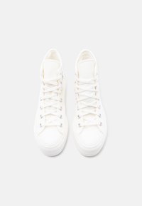 Ζευγάρι λευκά ψηλά παπούτσια στυλ sneakers με δεμένα προσεκτικά κορδόνια, απεικονιζόμενα από πάνω σε απλό ανοιχτό φόντο.