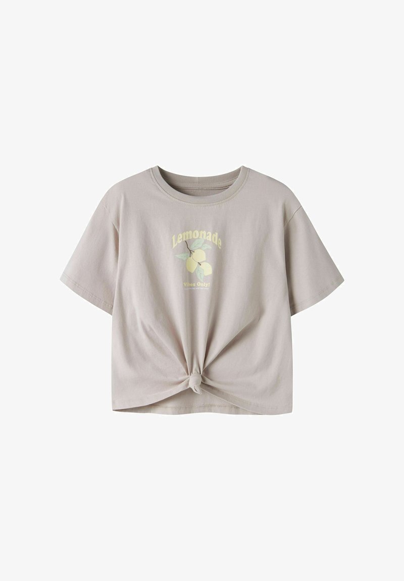 Ανοιχτό μπεζ κοντομάνικη μπλούζα με κόμπο μπροστά, γραφικό λεμονιού και το κείμενο "Lemonade Vibes Only" στο στήθος.