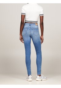 Kapelevat siniset farkut korkealla vyötäröllä, vaaleassa denimi pesussa ja takataskuilla. Yhdistetty valkoisen crop-topin ja harmaiden urheilukenkiä kanssa.