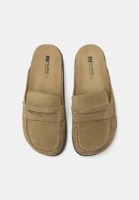 Pantofi slip-on din suede maro, cu vârf rotund și un detaliu cusut pe partea din față. Talpă plată din cauciuc negru, cu finisaj texturat.