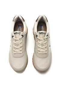 Zapatillas beige con parte superior de lona, cordones crema, acentos marrones y suela de goma. Cuenta con un collar acolchado y una plantilla texturizada.