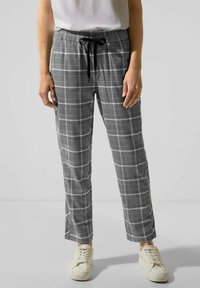 Grijze en zwarte geruite broek met een elastische tailleband en trekkoord, met een relaxte pasvorm en een gladde textuur, gecombineerd met witte sneakers.