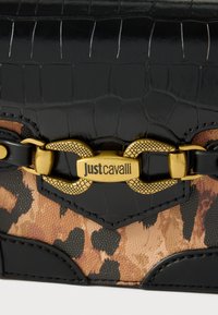 Crni ručak od kože s uzorkom krokodila, s naglaskom u bež boji s uzorkom leoparda, zlatni detalji s lancem za zatvaranje označenim "Just Cavalli."