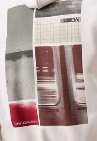 Felpa Calvin Klein Jeans con un collage di grafica astratta rossa e grigia, motivi a griglia e un'insegna della metropolitana con "2nd AVE."
