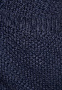 Marinblå stickad tyg med ett strukturerat mönster och ribbad kant, med en tät, mjuk väv och en jämn färg över hela ytan.