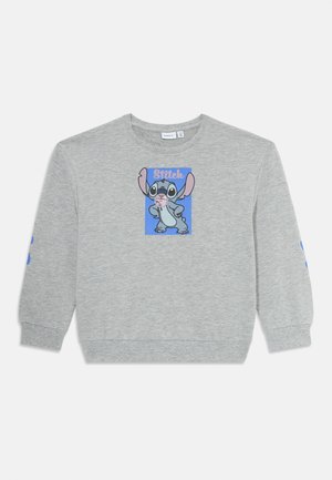 Vaaleanharmaa pitkähihainen collegepaita, jossa on sininen suorakaide, jossa on sarjakuvahahmo Stitch seisomassa kädet lanteilla ja vaaleanpunaista purukumia suussaan.