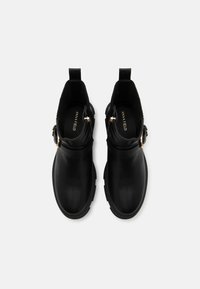 Mustad musta nahast ankle-kingad, mida iseloomustab sile nahapind, lukuga detail ja kuldse tooni metallosad. Ümarad varbad ja väike konts. Tekstureeritud siseruum.