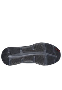 Semelle de chaussure en caoutchouc noir avec des motifs de grip texturés et une section centrale lisse. Présente un logo en rouge. Conçue pour la traction et la durabilité.