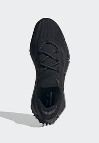 Black athletic shoe with a knitted upper, lace closure, textured detailing, and a rubber sole featuring traction studs.