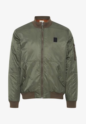 Olívazöld bomber dzseki elülső cipzárral, bordázott nyakkal és mandzsettákkal. Ujján zseb található, valamint egy fekete logófelvarró. Vízálló anyag.