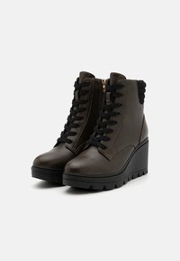 Brown leather ankle boots with black laces, wedge sole, and textured back. Features zipper detail and sturdy tread for traction.