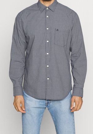 Koszula z długim rękawem na guziki, z granatowo-białym wzorem w kratę, kieszenią na piersi i zaokrąglonym dołem. Wykonana z tkaniny z bawełnianej mieszanki.