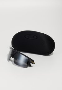 Schwarze Sportsonnenbrille mit elegantem Design, grauen Gläsern und goldenen Akzenten, begleitet von einem strukturierten schwarzen Schutzhülle.