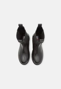 Stivali alla caviglia in pelle nera con una finitura liscia, pannelli laterali elasticizzati e linguette per una facile indossabilità. Punta arrotondata e suola con design testurizzato.