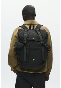 Schwarzer Rucksack mit mehreren Fächern, verstellbaren Trägern und einer oberen Klappe. Leichtes Material mit silbernem Logodetail und Kordelzugverschluss.