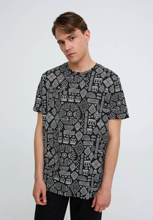 T-shirt nera con intricati motivi geometrici bianchi. Collo tondo, maniche corte e vestibilità ampia, realizzata in tessuto morbido.
