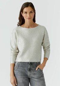Pull en argent texturé avec un col large et des manches longues, associé à un jean en denim délavé, avec des poches avant.