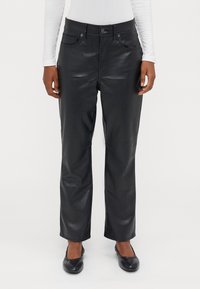 Calças de imitação de pele pretas com um design de perna reta, bolsos frontais e botões de metal prateado. A superfície tem uma textura lisa e brilhante.