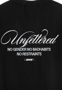 Camiseta negra con texto bordado en blanco. El diseño incluye la palabra "Unfettered" y las frases "Sin género, sin malos hábitos, sin restricciones."
