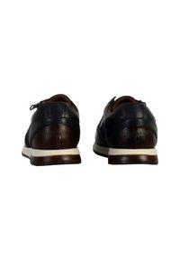Donkere leren schoenen met een glanzende afwerking, bruine accenten op de hak, witte rubberen zool en decoratieve stiksels. Klassiek vetersluitingssysteem.