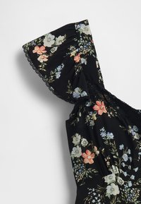 Kvetinové šaty s čiernym pozadím, ktoré majú volánikový výstrih, čipkovú lemovku a viacfarebné kvety v ružovej, modrej a krémovej farbe.