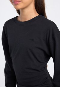 Zwart longsleeve t-shirt van katoen met een ronde hals, voorzien van een subtiel zwart logo aan de voorkant, een gladde textuur en een ontspannen pasvorm.