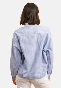 Chemise bleu à rayures fines avec des rayures texturées et des accents de pois argentés, avec une coupe décontractée et des manches longues. Vue arrière affichée.