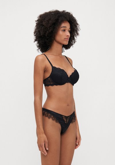 Black lace bralette with padded cups and adjustable straps, paired with matching lace-trimmed thong. Sleek, smooth fabric throughout.